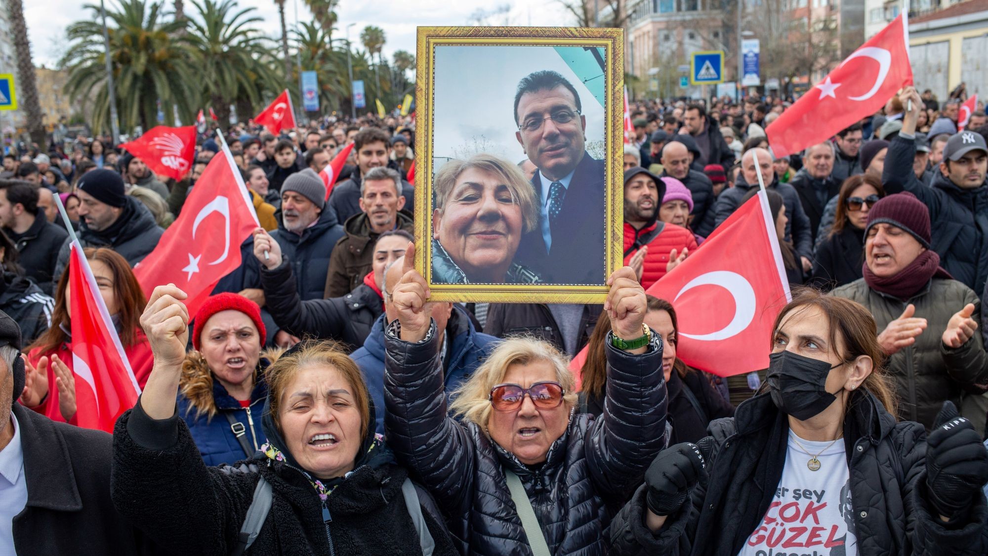 Frauen protestieren mit türkischen Flaggen. Eine hält ein Bild von sich und Ekrem İmamoğlu. 