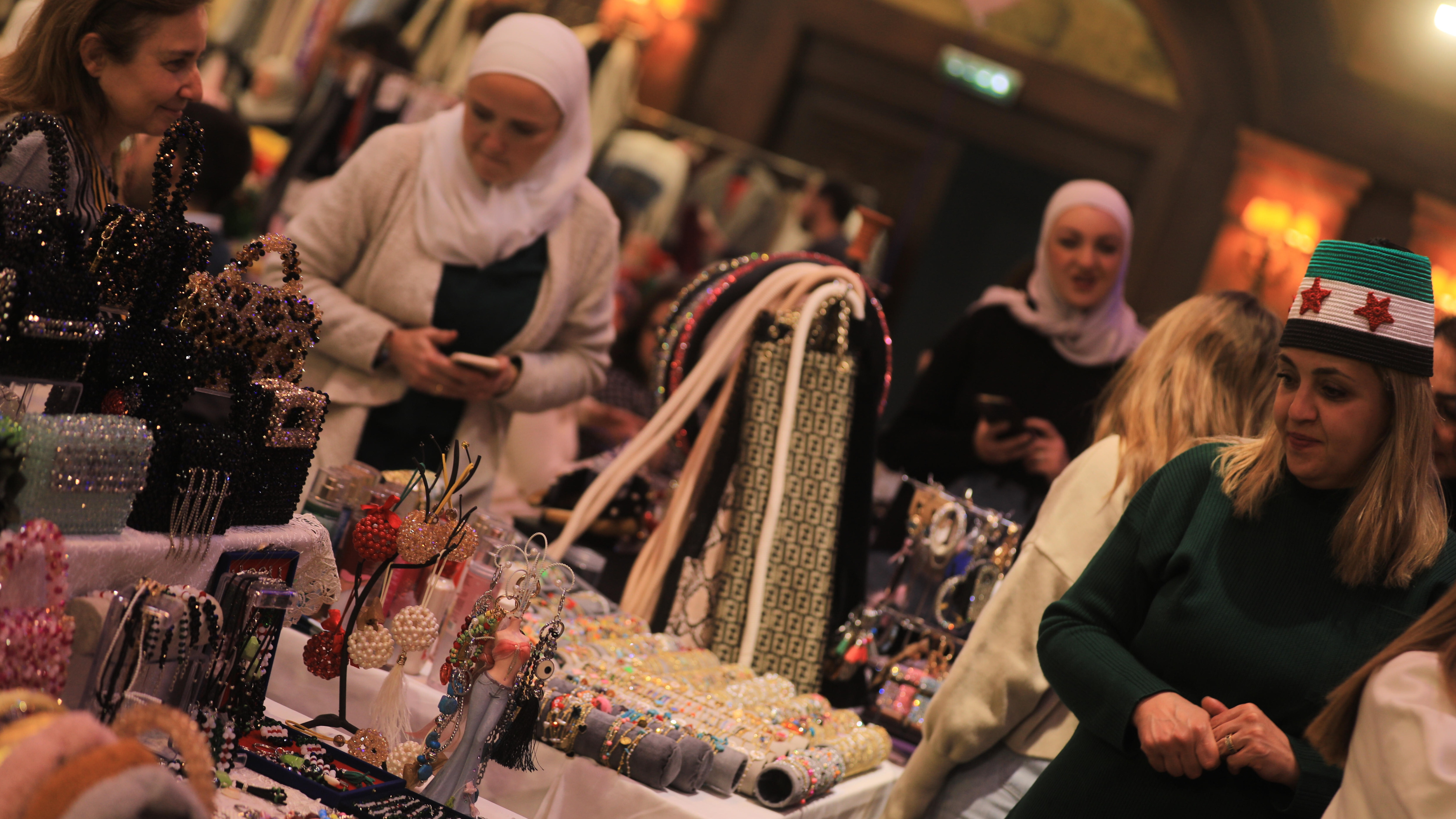 A group of women stand around a table upon which a number of handicrafts are placed for sale.