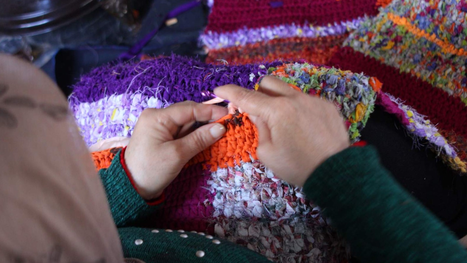 A women crochets a colour blanket.