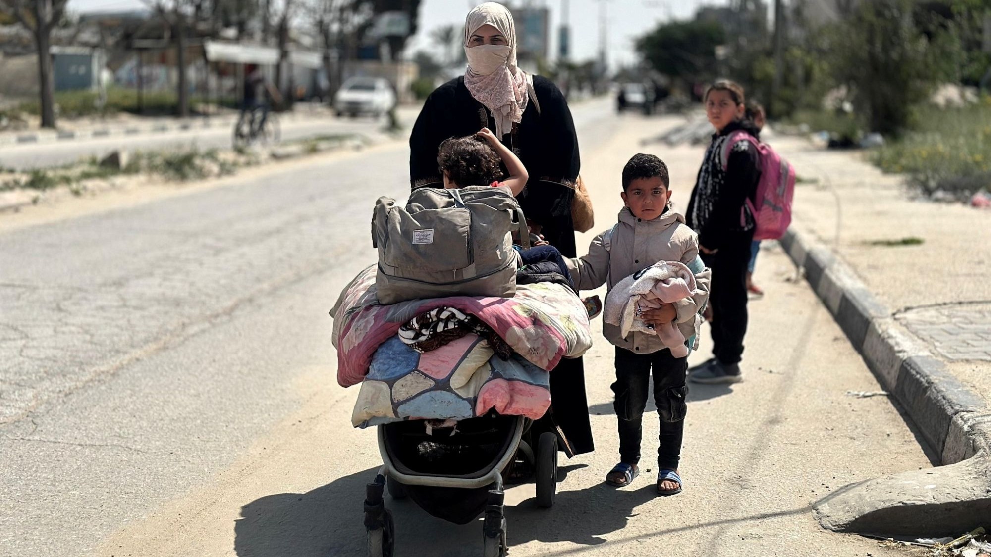 امرأة فلسطينية وأطفالها الثلاثة يفرون من الحرب في رفح، في يونيو/حزيران 2024. (Photo: Qantara/Doaa Shaheen) امرأة شوهدت في الشارع مع أطفالها الثلاثة.