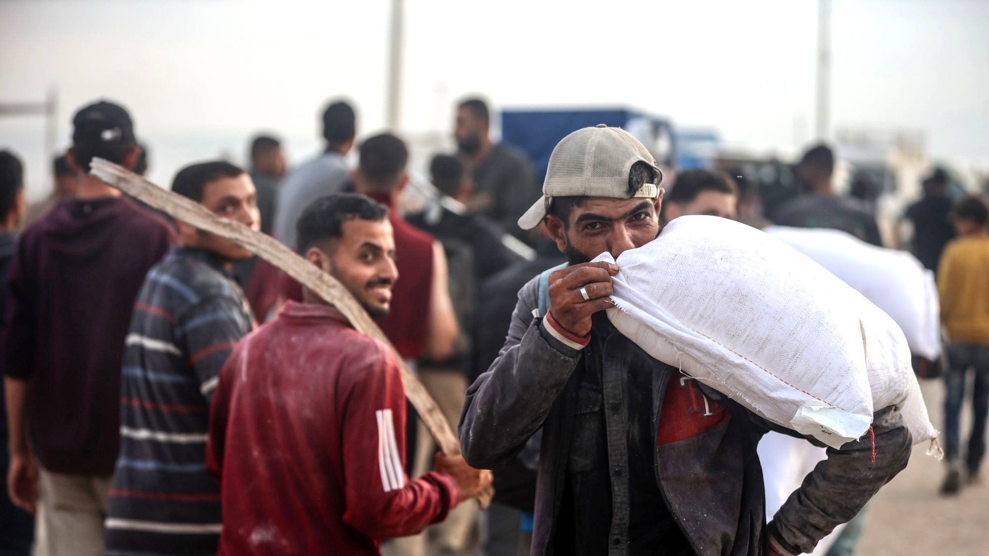 Nahrungsmittel erreichen Gaza-Stadt, 10. Juni 2025. (Foto: Picture Alliance / NurPhoto | M. Fathi) Ein Mann mit Baseballcap trägt einen Sack Mehl und küsst ihn.