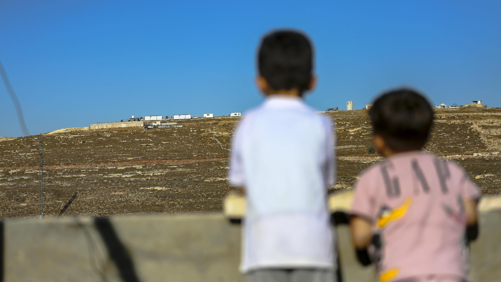 Israelische Siedlungen im Westjordanland (Foto: picture alliance / Middle East Images | Mosab Shawer) Zwei kleine Jungen schauen von einem Hausdach auf Siedlungen im Westjordanland