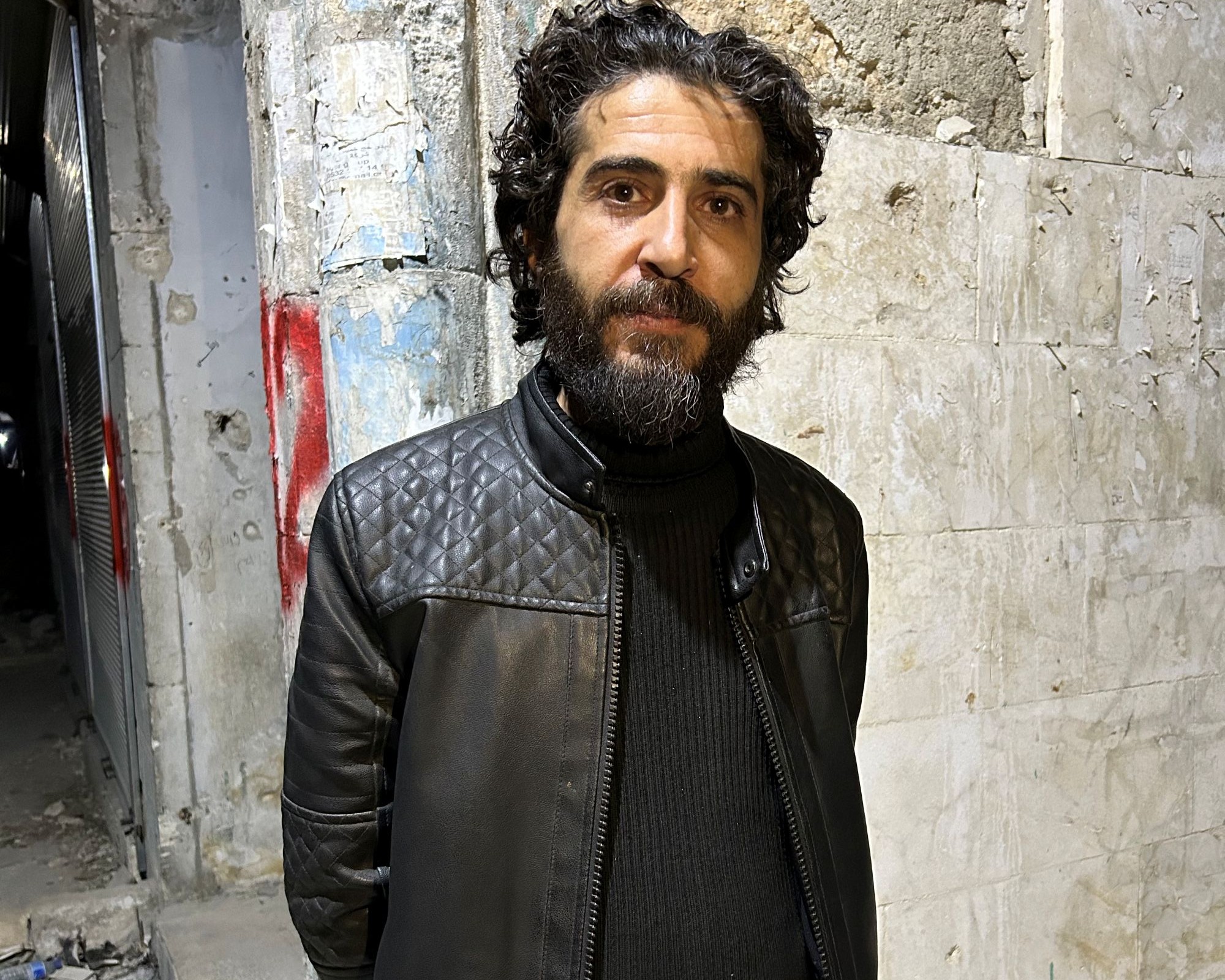 الناشط السوري أحمد الجلال. (Photo: Qantara/Kristin Helberg) رجل بلحية كثيفة وسترة الجلدية السوداء، وشعر داكن مجعّد مسرّح إلى الخلف.