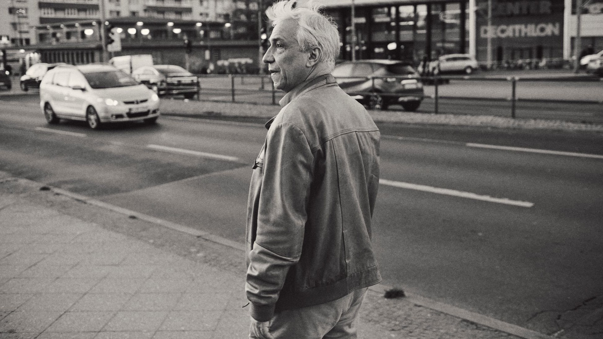 Yassin al-Haj Saleh in Berlin (Foto: U. Zintel) Ein Mann in Lederjacke vor einer befahrenen Straße, in schwarz-weiß.