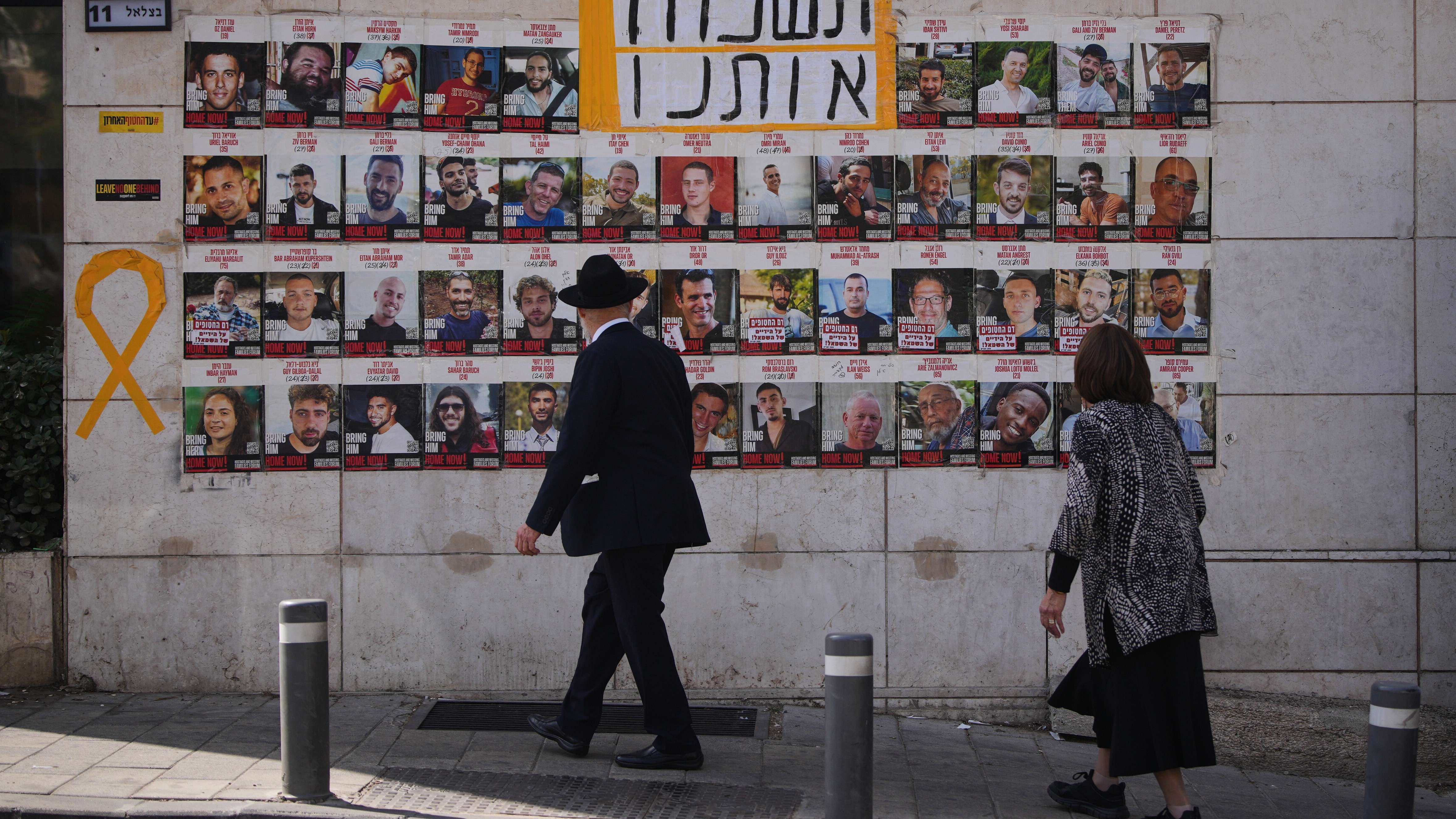 Eine Frau und ein Mann schauen auf die Fotos der Geiseln in Jerusalem