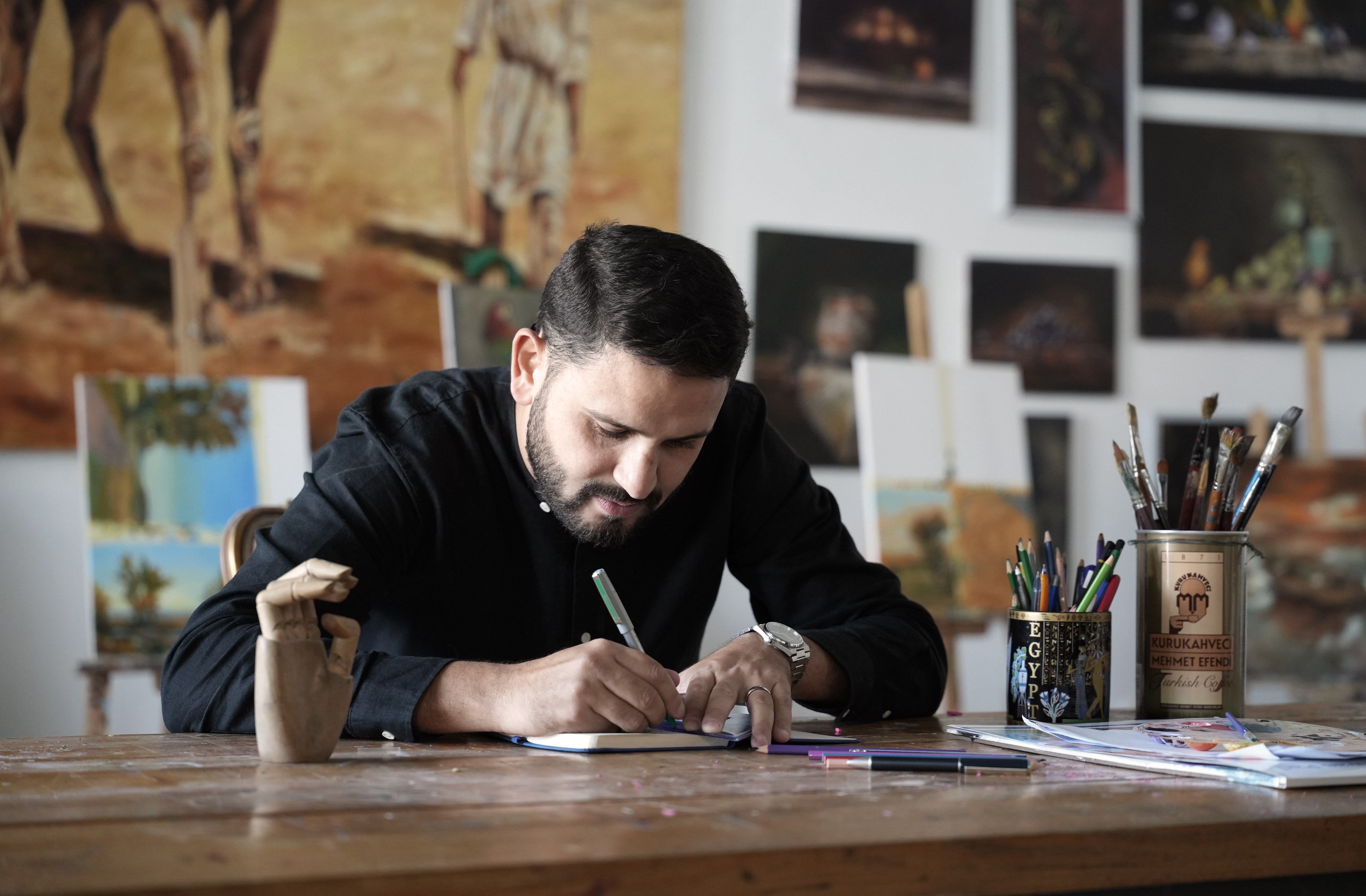 A man sits at a desk writing in a notepad.