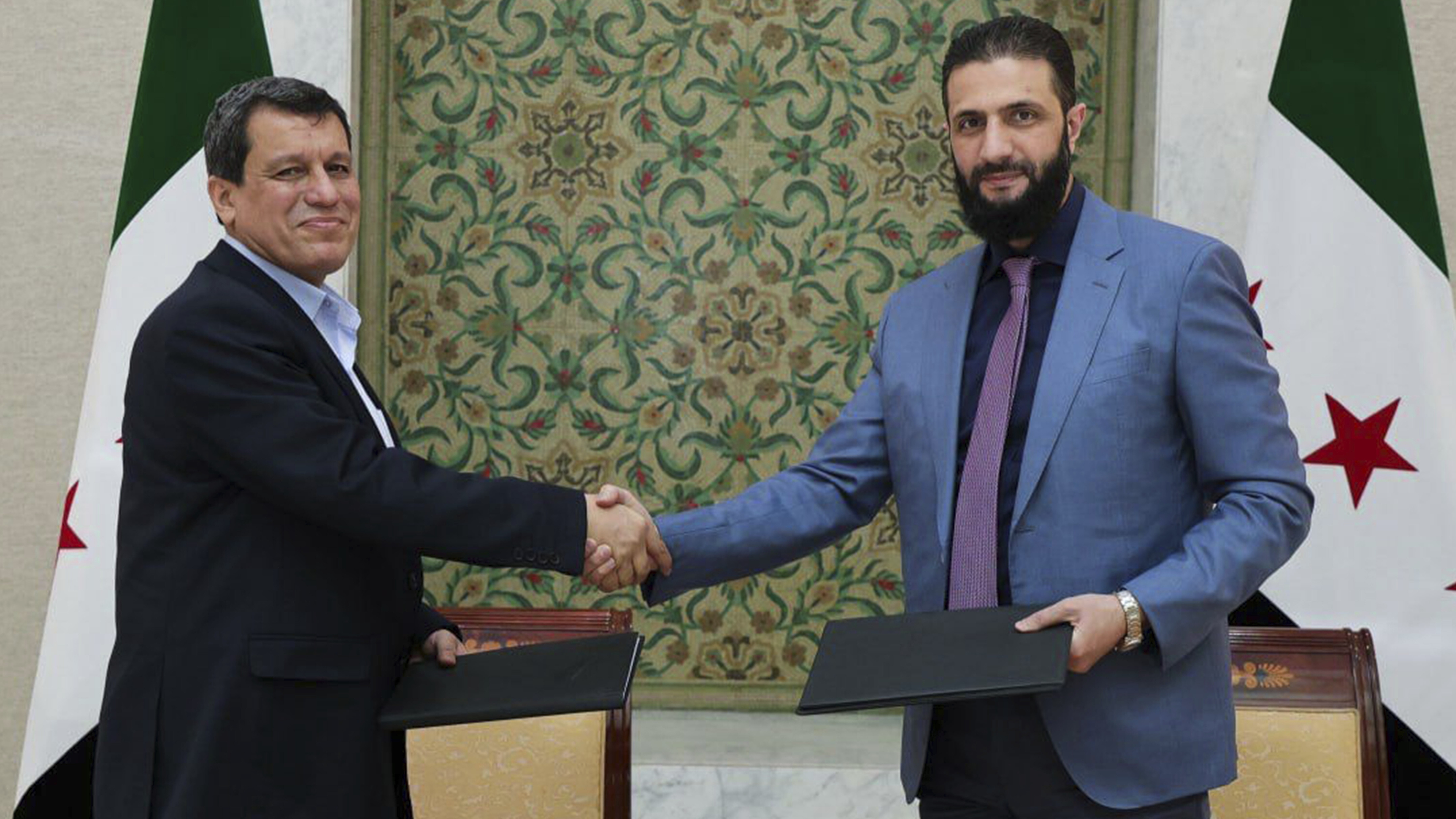 Mazlum Abdi und Ahmed al-Sharaa gebe sich die Hand, Oktober 2025. (Foto: picture alliance / AP | Uncredited)