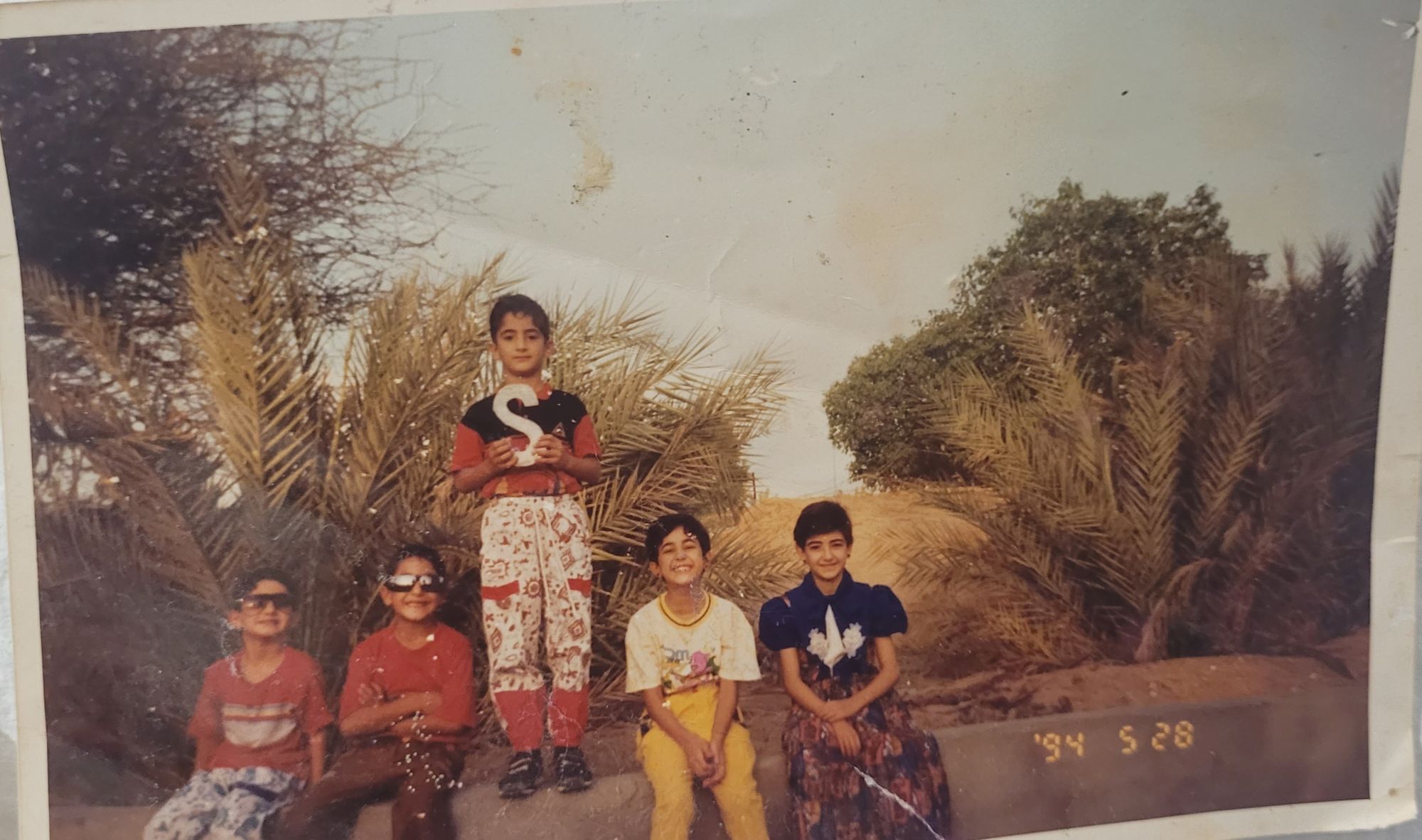 صورة تبدو قديمة لمجموعة من الأطفال يجلسون على حافة طريق.