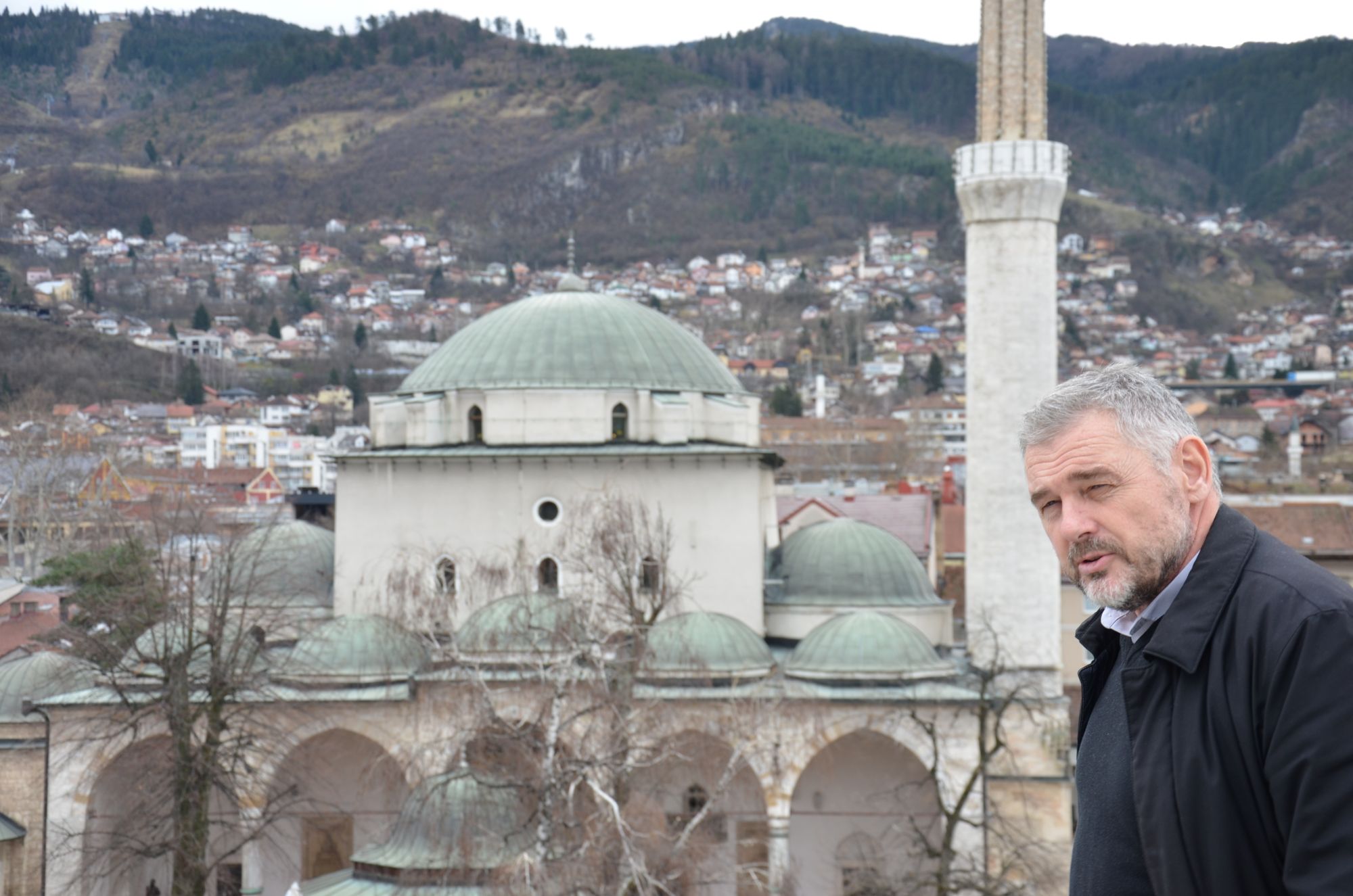 A man stands in front of a mosque.
