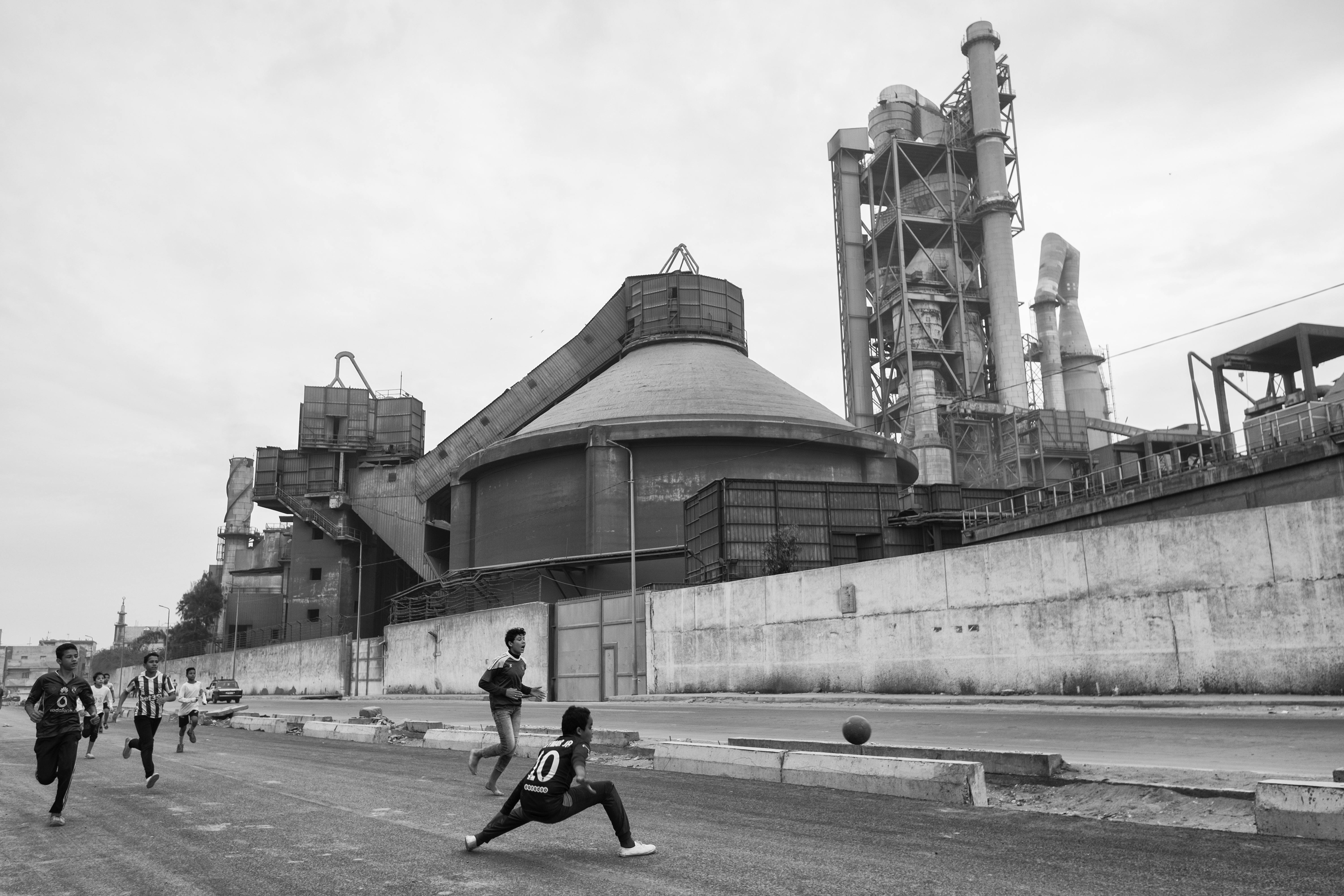 أطفال يلعبون كرة القدم أمام مصنع للأسمنت. (Photo: Mohamed Mahdy)