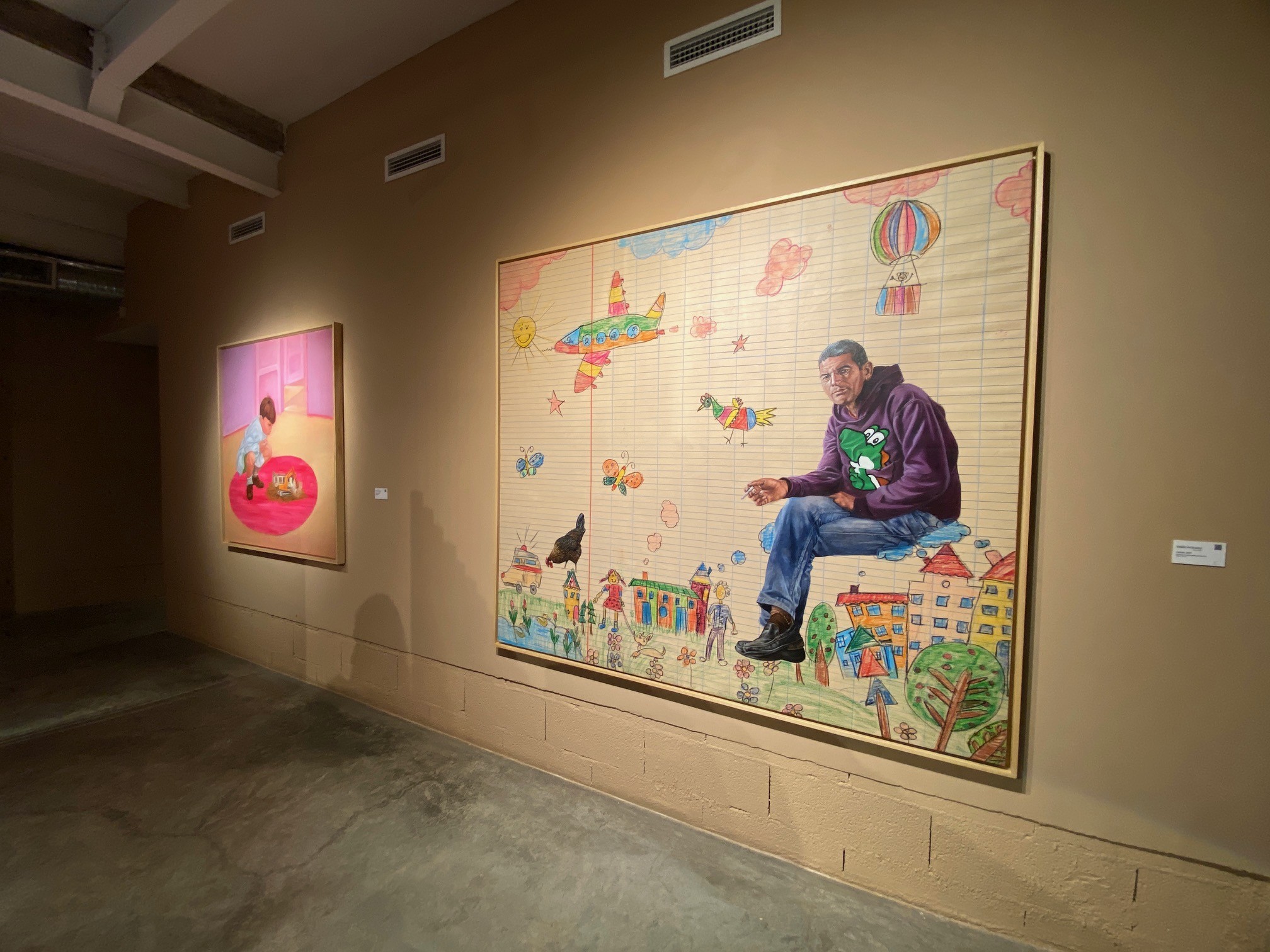 Two paintings hang on a wall in a gallery.