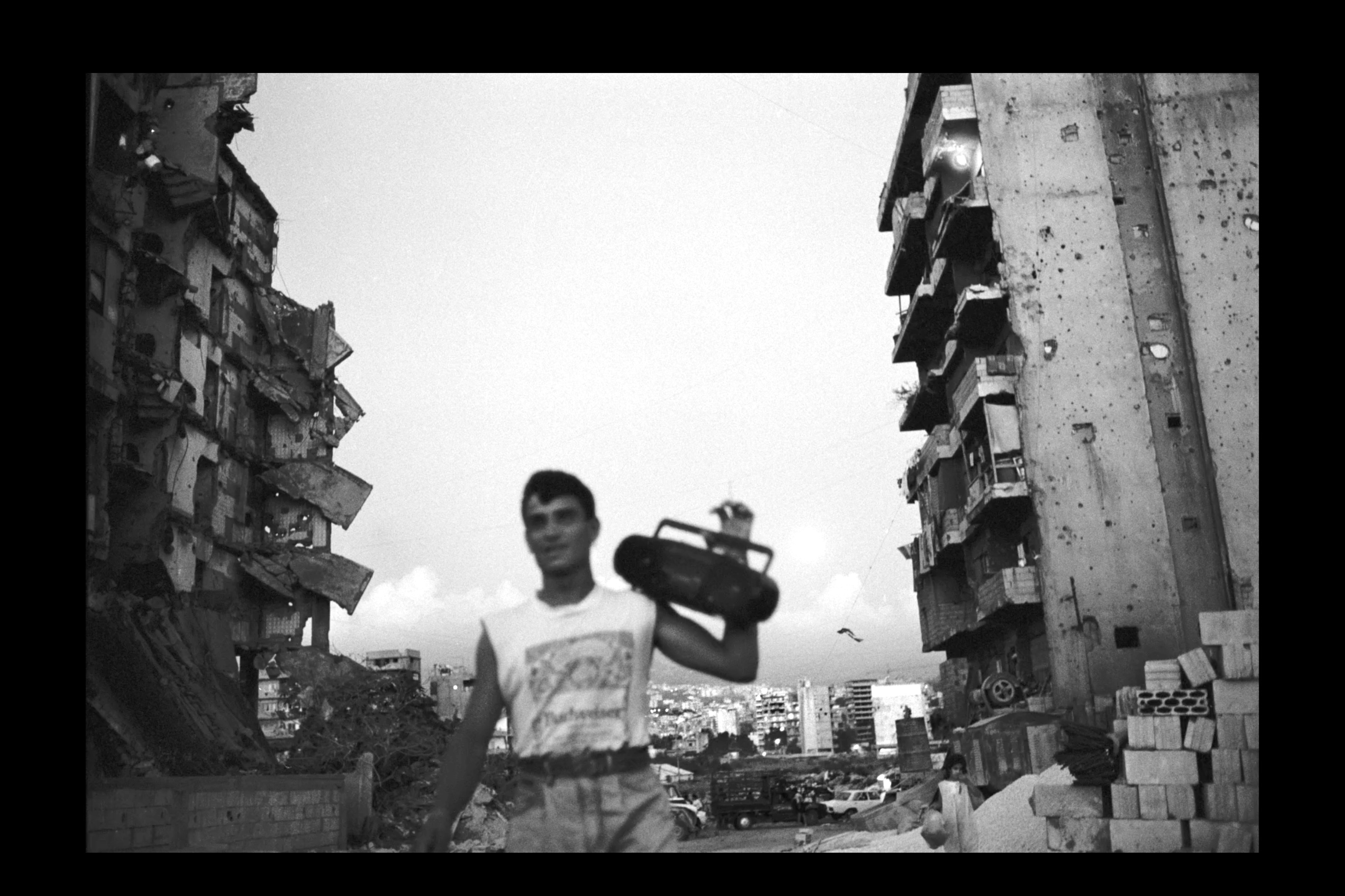 Ein Mann mit Ghettoblaster vor zerstörten Häusern, (Foto: Fouad Elkoury)