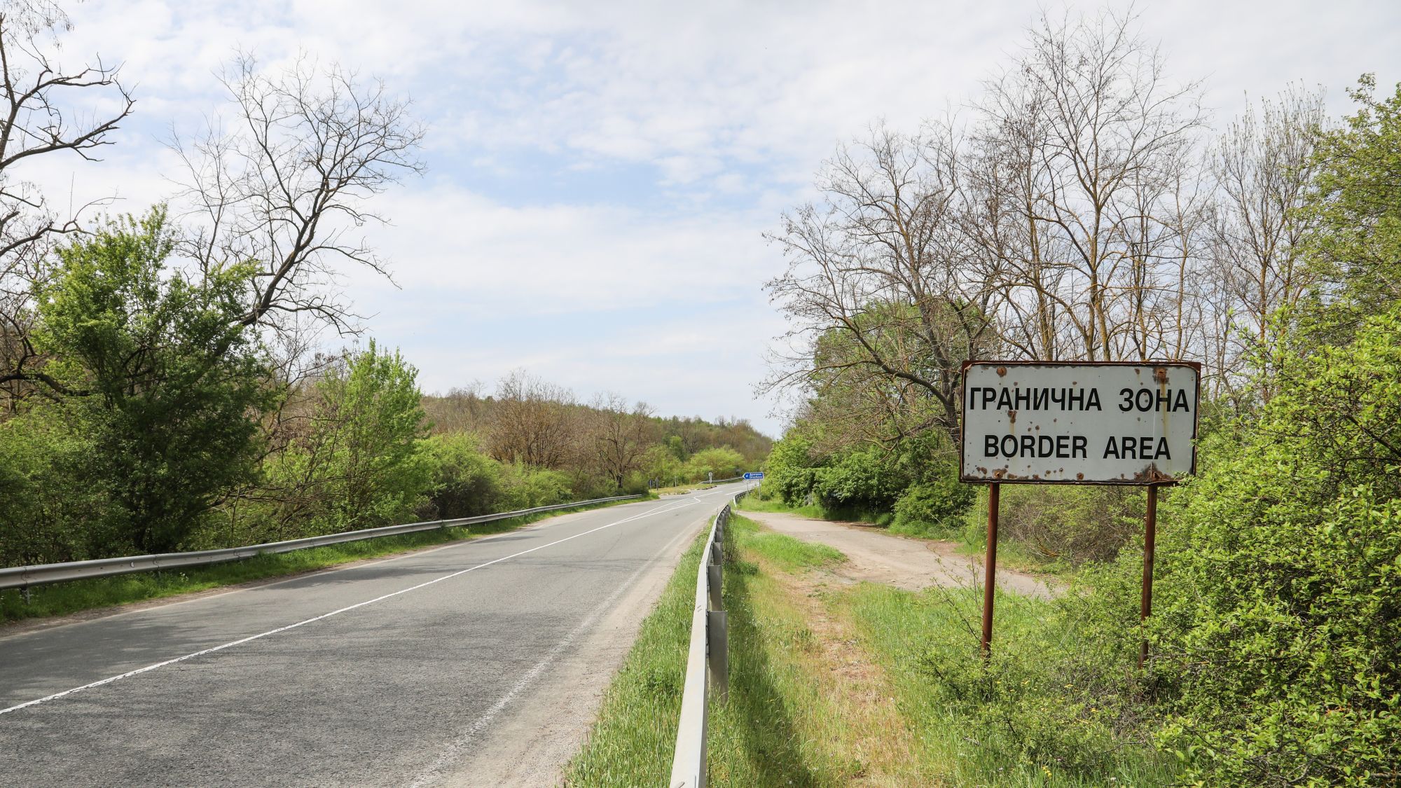 Eine Straße, rechts davon steht ein Schild mit der Aufschrift "Grenzregion" auf Englisch und Bulgarisch.