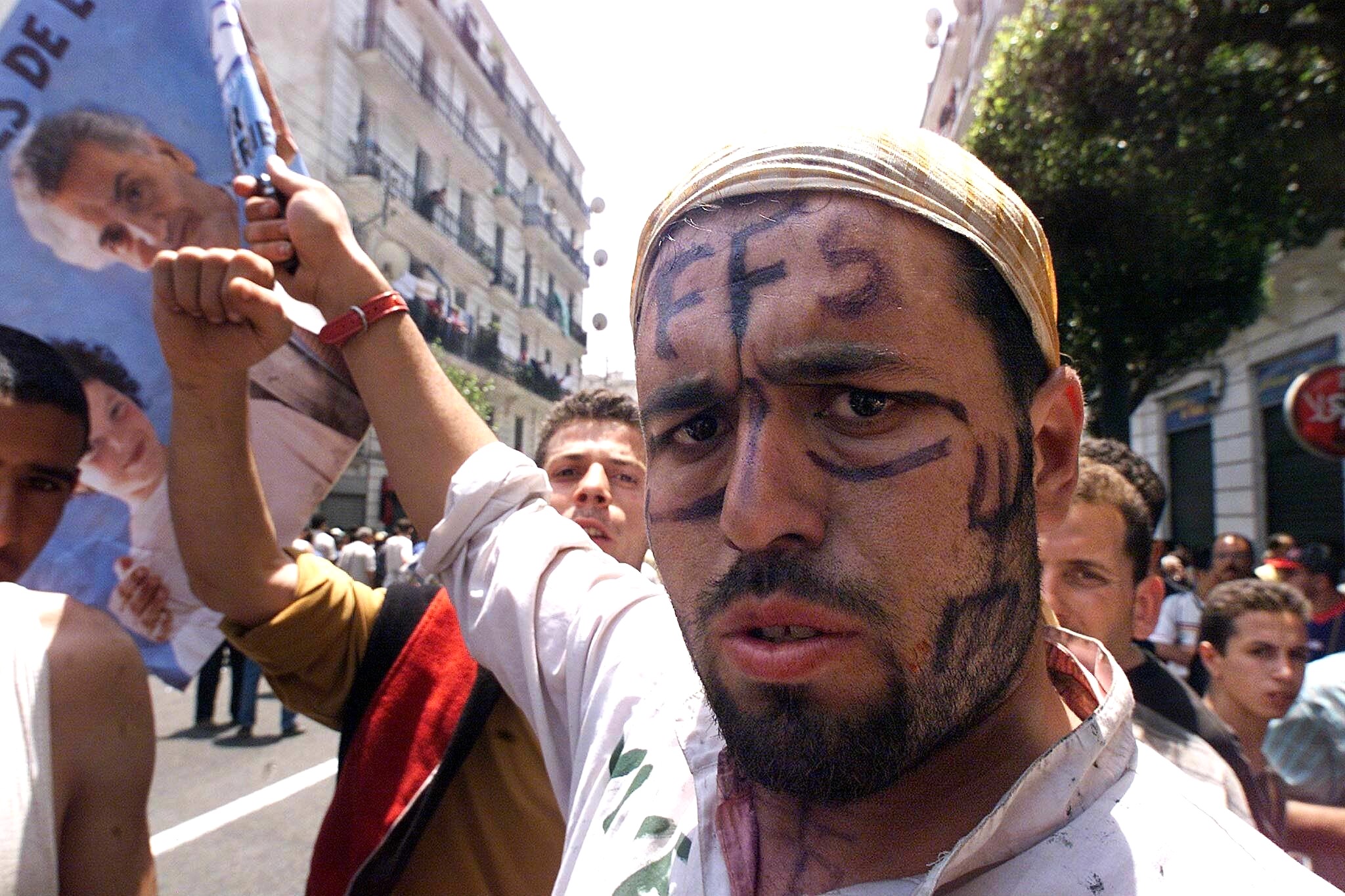 A man, whose face is covered with the FFS sign and Berber symbol on his cheek) marches with more than 200,000 people 31 May 2001 in Algiers to denounce what they describe as the repression of Berber people in Algeria's northeastern Kabylia region. 
