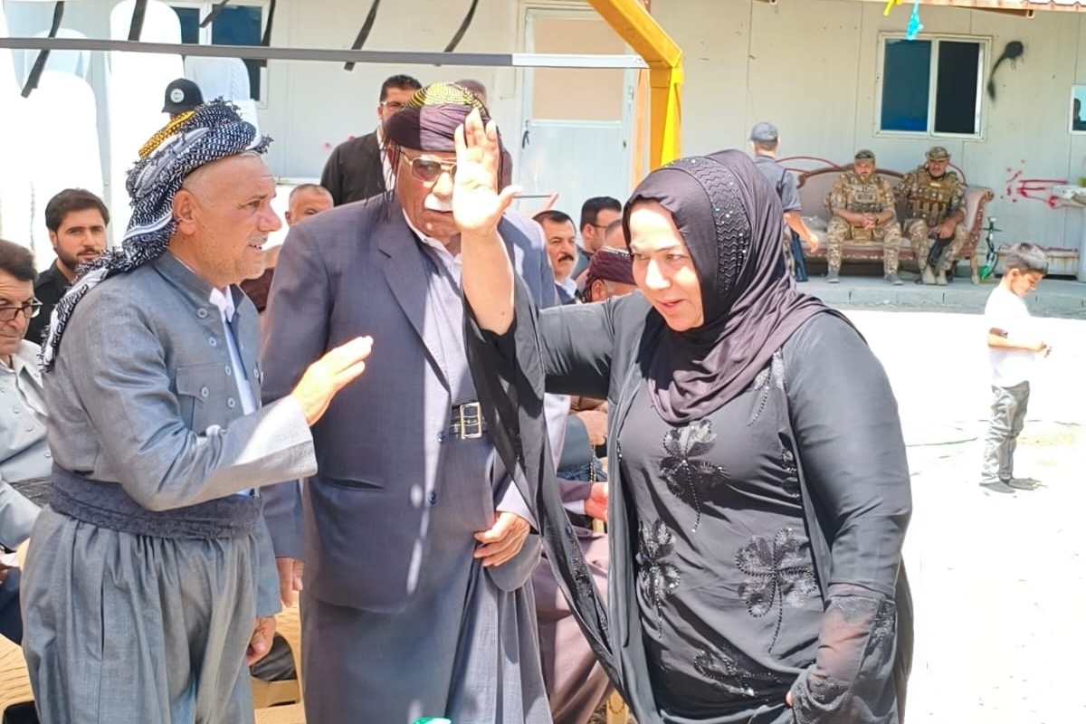 A woman raises her hand to greet people.