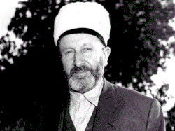 back and white photo of a man in a suit, wearing a white turban and a beard.