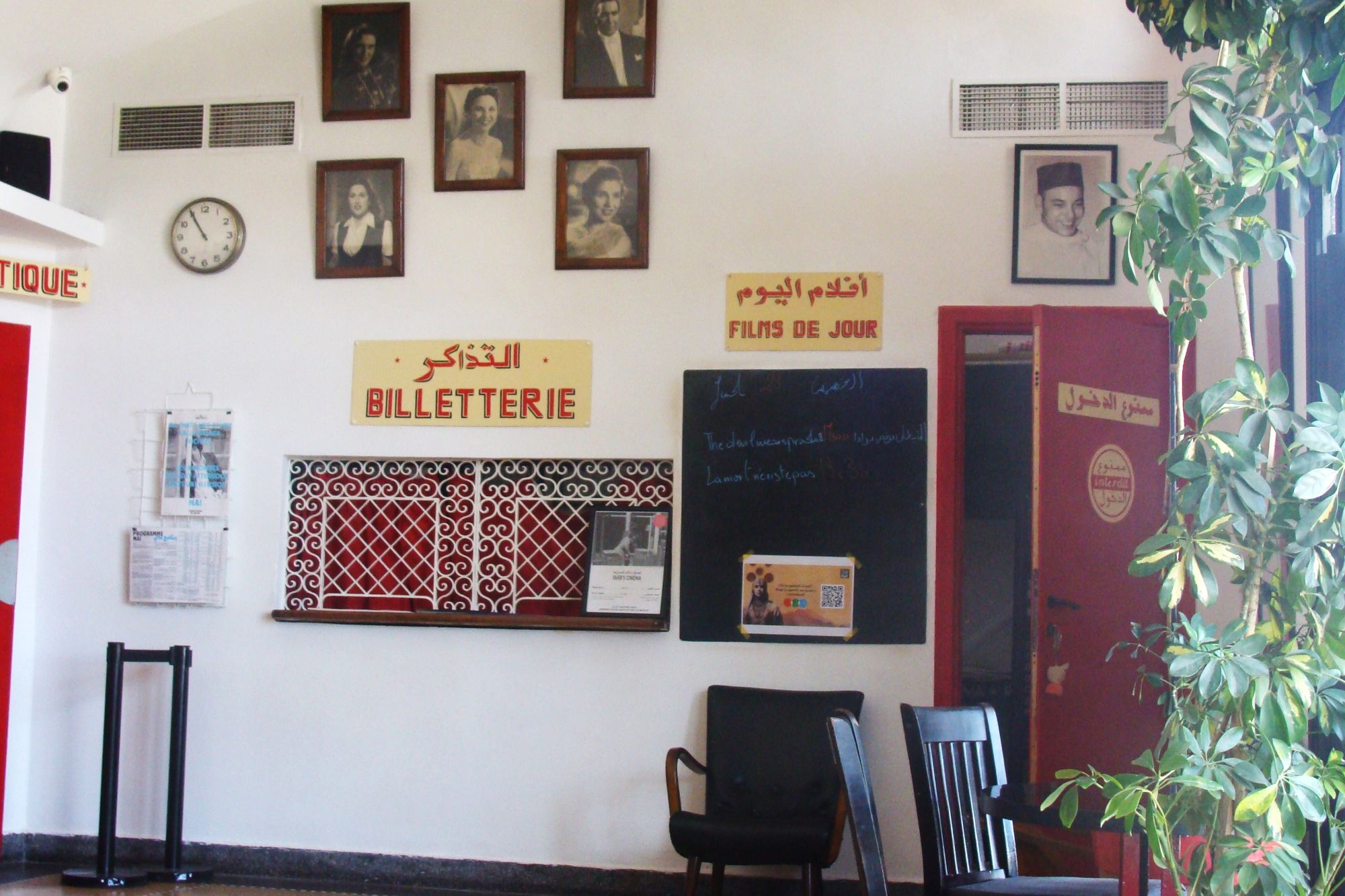 A ticket office, with black and white images of famous people above the counter.