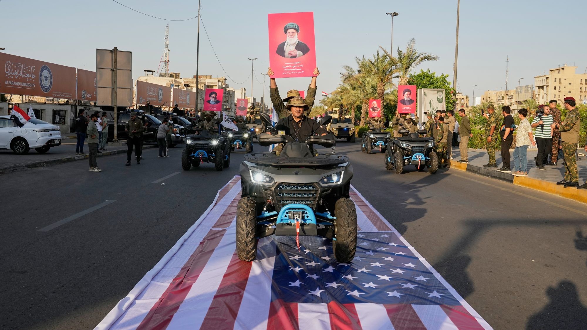 عناصر من قوات الحشد الشعبي العراقية يحملون صورة لآية الله علي خامنئي أثناء مرورهم فوق علم أمريكي في بغداد، 1 أكتوبر/تشرين الأول 2026.