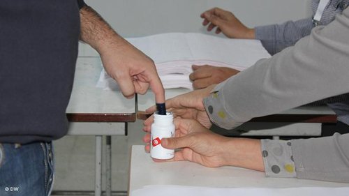 A voter dipping his finger into a pot of purple indelible ink after casting his vote (photo: Mounir Souissi/DW)