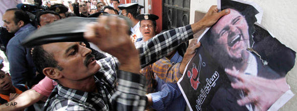 A Syrian protester beats with a shoe on a poster showing President Bashar al-Assad (photo: AP)