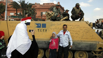 Demonstrators in Tahrir Square taking souvenir photos in front of tanks (photo: AP)