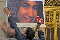 Two men post a large-size photograph of murdered Marwa El Sherbini on a wall (photo: dpa)