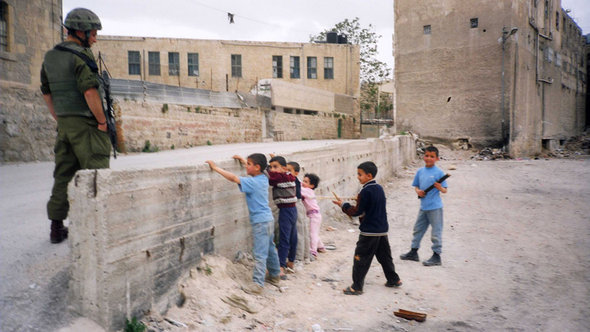 Palestinian children enact a checkpoint control scene in front of an Israeli soldier (photo: © Breaking the Silence)