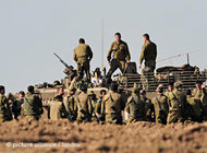 Israeli soldiers get together beside an armoured vehicle outside the northern Gaza Strip, 10 January 2009 (photo: picture alliance/dpa)