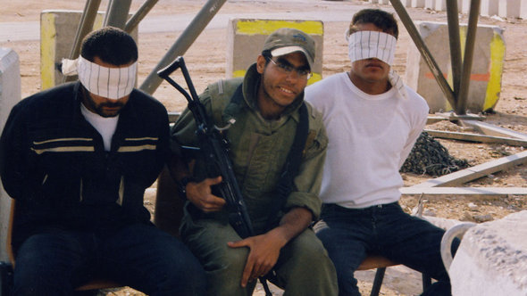 An Israeli soldier posing with blindfolded Palestinian prisoners (photo: © Breaking the Silence)