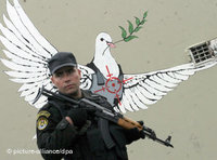 Palestinian security agent in front of a graffiti of a peace dove (photo: dpa) 
