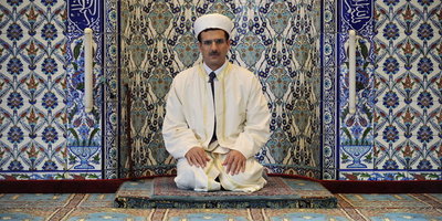 An imam kneeling in front of a prayer niche (photo: dpa)