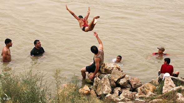 فِتيان وشباب عراقيون يسبحون في نهر دجلة هرباً من حرّ الصيف في بغداد يونيو/ حزيران 2010 . أ ب
