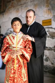 A boy with a candle and a priest during the ceremony (photo: Iason Athanasiadis)