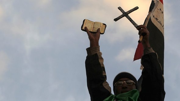 أحد معارضي الرئيس محمد مرسي يرفع القرآن والصليب عالياً أمام القصر الرئاسي. رويترز