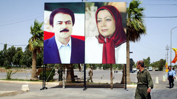 An Iranian militant of the opposition People Mujahedin Organization of Iran (PMOI) looks at pictures of leaders Maryam Rajavi (L), president of the National Council of Resistance of Iran, the political wing of the PMOI and her husband Massoud Rajavi as he walks to attend a gathering at camp 'Ashraf City', near the restive city of Baquba, northeast of Baghdad, 17 June 2006