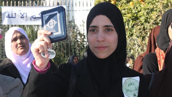 Woman with a headscarf in Tunisia holds up a copy of the Koran (photo: DW)