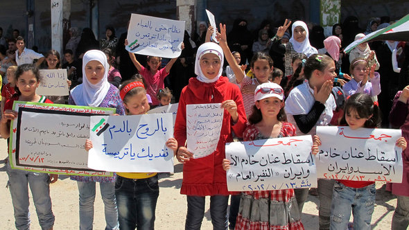 Girls hold signs and shout slogans against Syria's President Assad in Bennish, near Idlib (photo: REUTERS/Abdo)