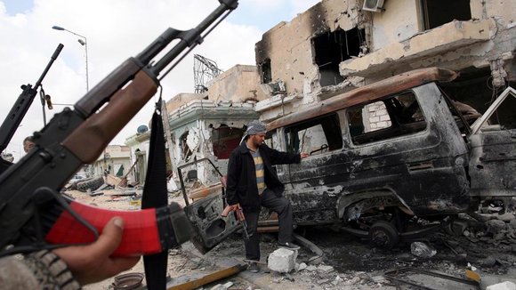 Lybian rebels in Misrata standing in front of a damaged car (photo: picture alliance/dpa)