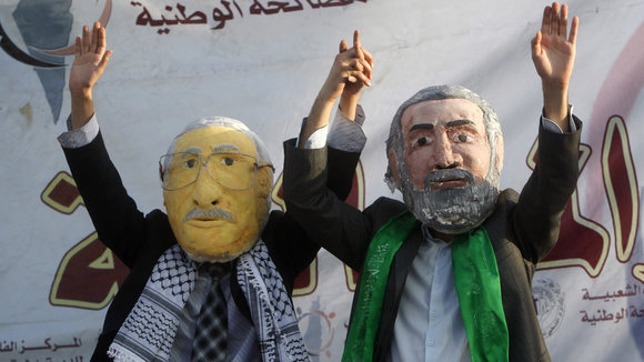 متظاهران فلسطينيان يرتديان قناعي عباس وهنية ويدعوان لوحدة الصف الفلسطيني. 