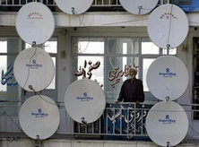 Traditionell gekleideter Afghane auf einem Balkon, umringt von Satellitenschüsseln; Foto: AP