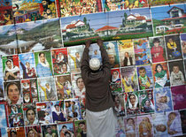 Pakistanischer Verkäufer hängt ein Poster der ermordeten Oppositionsführerin Buttho auf, Foto: AP