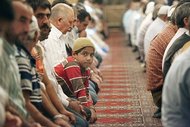 Young boy in the middle of a row of praying men in a mosque (photo: dpa)  