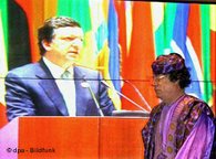 Muammar al-Ghaddafi vor einem Monitor, auf dem Manuel Barroso zu sehen ist; Foto: dpa