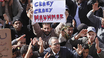 متظاهر يرفع شعار: القدافي المجنون. الصورة: د ب ا