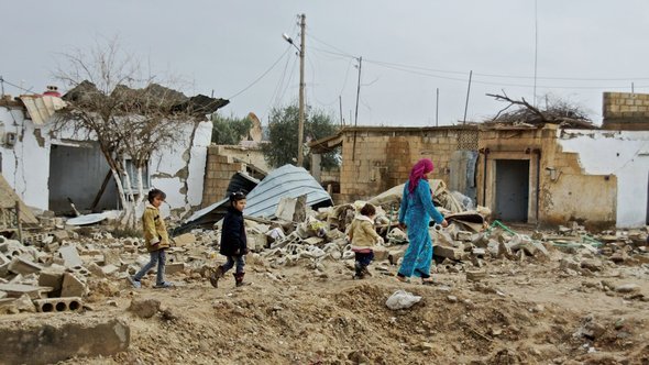 مدنيون سوريون في قرية مدمرة. دويتشه فيله.