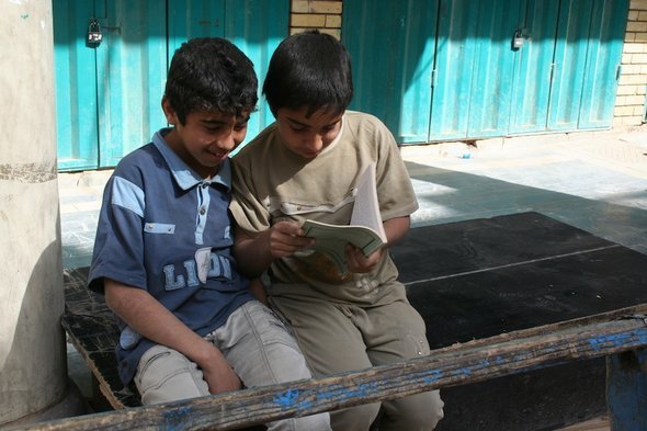 Two young boys reading a book on Mutanabbi Street in Baghdad (photo: Munaf al-Saidy)
