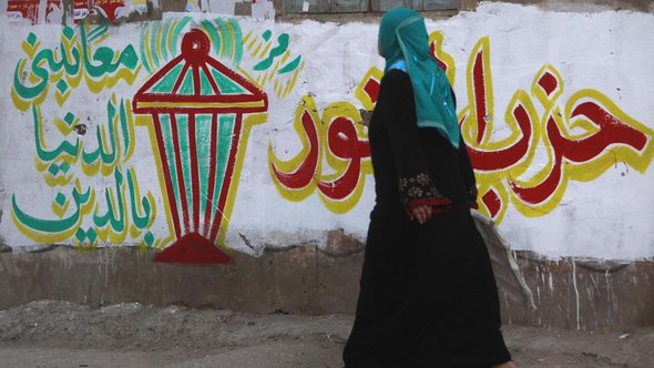 Woman passes by Salafist graffiti in El-Qalubia (photo: Reuters)