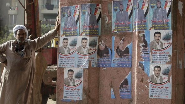 Man standing next to a wall with candidate posters of the Nour Party (photo: AP)