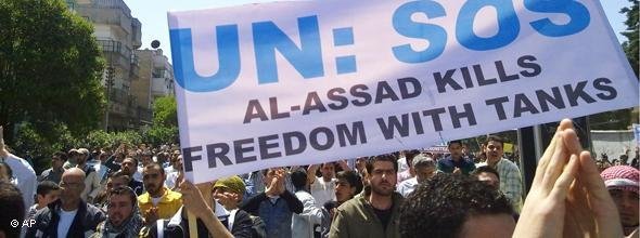 Syrian protesters hold a poster saying 'Assad kills freedom with tanks' (photo: AP)