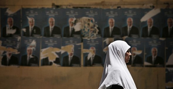 An Egyptian woman walks past election posters in Egypt (photo: AP)